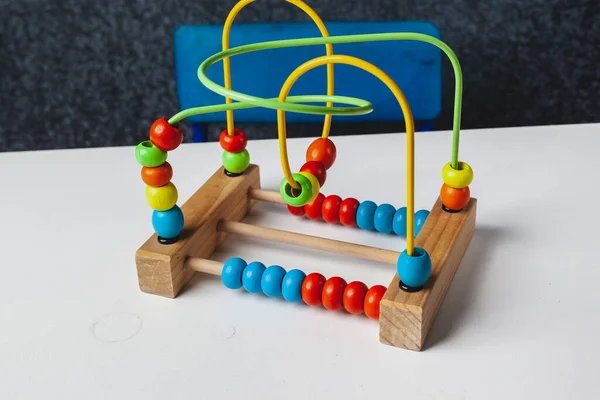 Çocuk Montessori oyunu oynuyor. Çocuk tahta oyuncak ayırıcı topluyor. Çok renkli geometrik daireler ve ovaller. Erken çocukluk gelişimi. İnce motor becerilerin geliştirilmesi için mantıklı bir labirent.