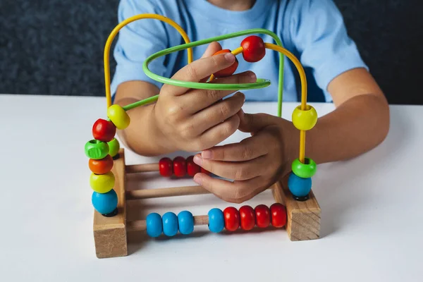 Çocuk Montessori oyunu oynuyor. Çocuk tahta oyuncak ayırıcı topluyor. Çok renkli geometrik şekiller, daire, kare, üçgen, dikdörtgen.