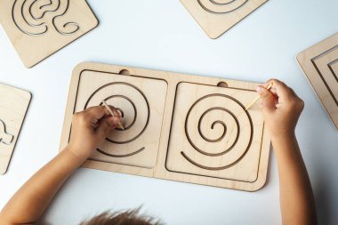 Çocukların tahta oyuncağı. Beynin interhemisferik gelişimi için bir tahta. Çocukların elleri, yakın plan. Çocuk gelişimi gecikmesi. Konuşma terapisti için ahşap labirent. Çocuk için Montessori Oyunları 