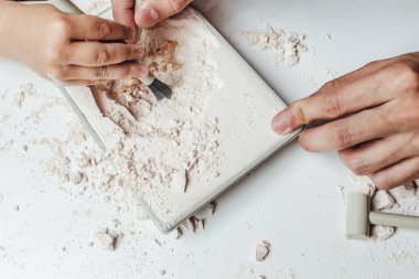  Çocuk kazılmış bir arkeoloğu oynuyor. Eller yukarı. Anaokulunda ve erken çocukluk ortamında arkeoloji kazı setiyle eğlenen çocuklar. 