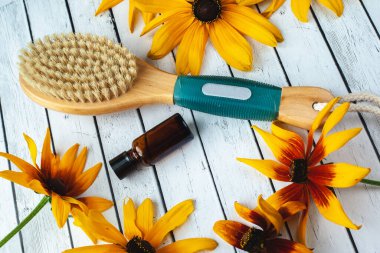 Kuru vücut masajı için selülit önleyici fırça ve arka planda aromaterapi yağları. Vücut spası