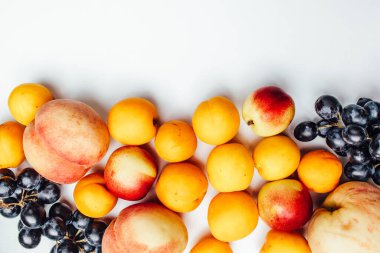 Beyaz arka planda meyve şeftalileri, kayısılar ve üzümler.