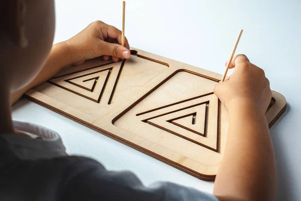 Montessori wooden game for the development of children.Children\'s wooden toy. Board for interhemispheric development of the brain. Children\'s hands close-up. Child development retardation.