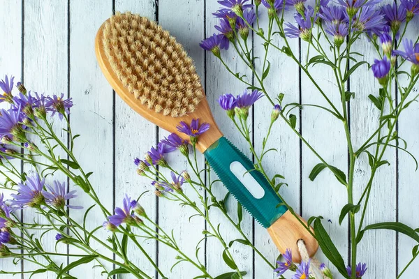 Anti-cellulite body brush with flowers lies on the background of boards. Body spa
