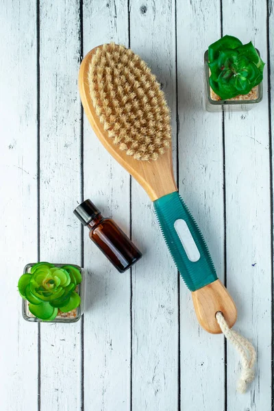 Anti-cellulite brush for dry body massage and aromatherapy oils on the background of boards. Body spa