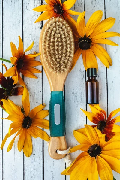 Anti-cellulite brush for dry body massage and aromatherapy oils on the background of boards. Body spa