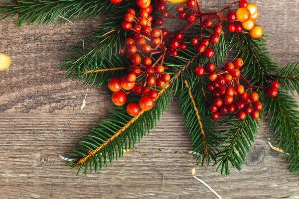 Christmas blank for your advertisement, banner. Berries and spruce branches on wooden background