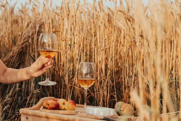 Summer outdoor recreation. Picnic in the wheat field. Aperol, peaches, grapes and cheese