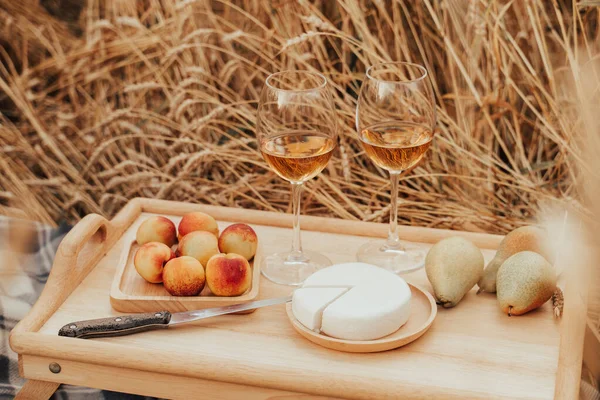 Summer outdoor recreation. Picnic in the wheat field. Aperol, peaches, grapes and cheese top view.