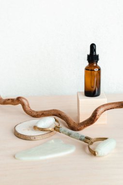 Kozmetik şişeler, yüz serumu, yüz masajı silindiri ve beyaz arka planda guache kazıyıcısı. Güzellik salonu reklamı, yüz masajı. Kırışıklıkları olmayan sağlıklı bir cilt. Tek renkli fotoğraf eğilimi 2020
