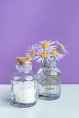 Alternatif şifalı bitkiler ve homeopatik küreseller. Homeopati tıp konsepti. Bir şişe homeopatik boncuk, şifalı bitkiler ve çiçekler. Homeopati ilacı..
