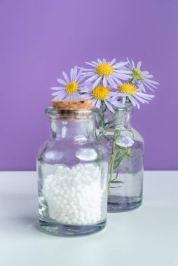 Alternatif şifalı bitkiler ve homeopatik küreseller. Homeopati tıp konsepti. Bir şişe homeopatik boncuk, şifalı bitkiler ve çiçekler. Homeopati ilacı..