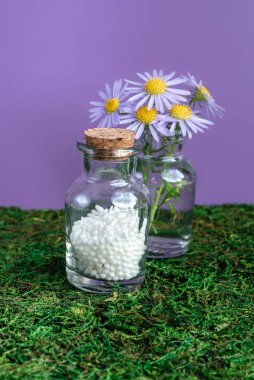 Alternatif şifalı bitkiler ve homeopatik küreseller. Homeopati tıp konsepti. Bir şişe homeopatik boncuk, şifalı bitkiler ve çiçekler. Homeopati ilacı..