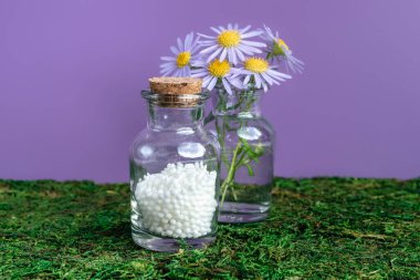 Alternatif şifalı bitkiler ve homeopatik küreseller. Homeopati tıp konsepti. Bir şişe homeopatik boncuk, şifalı bitkiler ve çiçekler. Homeopati ilacı..