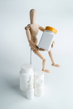 Küçük tahta adam ilaç kavanozunu tutuyor. Beyaz arkaplanda izole et. Tabletlerin reklamı. Mesaj için yer. Corona virüsü tedavisi. Mockup eczacılık konsepti