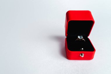 Nişan yüzüğü kırmızı hediye kutusunda, beyaz arka planda. Evlen benimle. Lüks aksesuar. Metin için yer. 