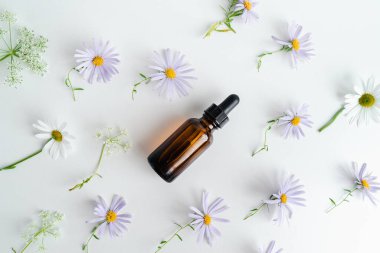 Unisex kozmetik. Mesaj için yer. Spa doğal organik ürünler. Erkekler ve kadınlar için anti-yaş kozmetik ürünleri. Çiçeklerin arka planında deri sağlığı için bir şişe öz ve surum. Doğal bitkisel cilt bakımı