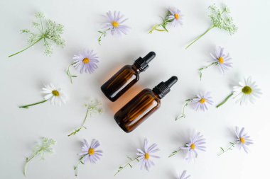 Unisex kozmetik. Mesaj için yer. Spa doğal organik ürünler. Erkekler ve kadınlar için anti-yaş kozmetik ürünleri. Çiçeklerin arka planında deri sağlığı için bir şişe öz ve surum. Doğal bitkisel cilt bakımı