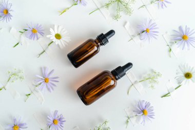 Unisex kozmetik. Mesaj için yer. Spa doğal organik ürünler. Erkekler ve kadınlar için anti-yaş kozmetik ürünleri. Çiçeklerin arka planında deri sağlığı için bir şişe öz ve surum. Doğal bitkisel cilt bakımı