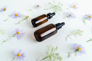 Unisex kozmetik. Mesaj için yer. Spa doğal organik ürünler. Erkekler ve kadınlar için anti-yaş kozmetik ürünleri. Çiçeklerin arka planında deri sağlığı için bir şişe öz ve surum. Doğal bitkisel cilt bakımı