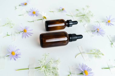 Unisex kozmetik. Mesaj için yer. Spa doğal organik ürünler. Erkekler ve kadınlar için anti-yaş kozmetik ürünleri. Çiçeklerin arka planında deri sağlığı için bir şişe öz ve surum. Doğal bitkisel cilt bakımı