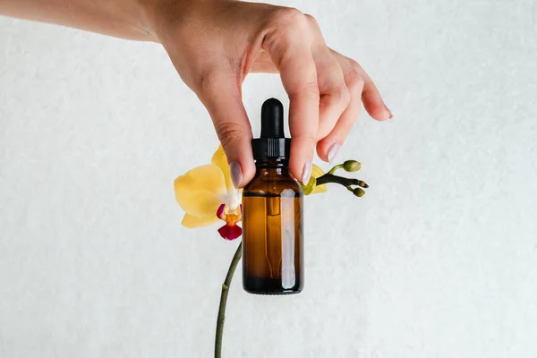 Jovem Tem Uma Essência Para Pele Nas Mãos Flores Orquídeas — Fotografia de Stock