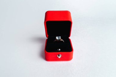 Beyaz arka planda kırmızı hediye kutusunda bir nişan yüzüğü. Evlen benimle. Lüks aksesuar. Metin için yer