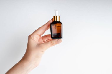 Genç bir kadın elinde yüz serumu tutuyor. Nar özlü yüz sağlığı için esans. Deri gerdirme için antidepresan kozmetik. Kırmızı cam şişeli serum. Organik Vegan Ürünleri. 