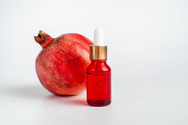 Nar özlü yüz sağlığı için esans. Deri gerdirme için antidepresan kozmetik. Kırmızı cam şişede serum ve nar arkaplanı. Organik Vegan Ürünleri. Metin için yer