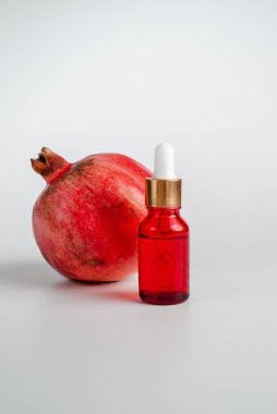 Nar özlü yüz sağlığı için esans. Deri gerdirme için antidepresan kozmetik. Kırmızı cam şişede serum ve nar arkaplanı. Organik Vegan Ürünleri. Metin için yer