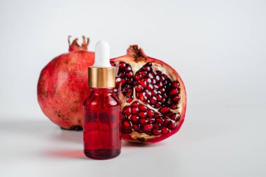 Nar özlü yüz sağlığı için esans. Deri gerdirme için antidepresan kozmetik. Kırmızı cam şişede serum ve nar arkaplanı. Organik Vegan Ürünleri. Metin için yer