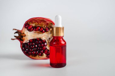 Nar özlü yüz sağlığı için esans. Deri gerdirme için antidepresan kozmetik. Kırmızı cam şişede serum ve nar arkaplanı. Organik Vegan Ürünleri. Metin için yer