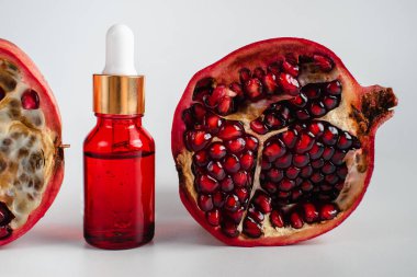 Nar özlü yüz sağlığı için esans. Deri gerdirme için antidepresan kozmetik. Kırmızı cam şişede serum ve nar arkaplanı. Organik Vegan Ürünleri. Metin için yer