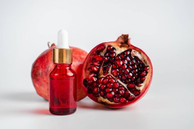 Nar özlü yüz sağlığı için esans. Deri gerdirme için antidepresan kozmetik. Kırmızı cam şişede serum ve nar arkaplanı. Organik Vegan Ürünleri. Metin için yer