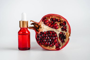 Nar özlü yüz sağlığı için esans. Deri gerdirme için antidepresan kozmetik. Kırmızı cam şişede serum ve nar arkaplanı. Organik Vegan Ürünleri. Metin için yer