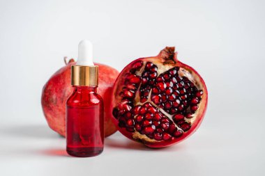 Nar özlü yüz sağlığı için esans. Deri gerdirme için antidepresan kozmetik. Kırmızı cam şişede serum ve nar arkaplanı. Organik Vegan Ürünleri. Metin için yer