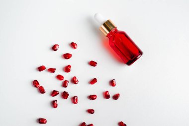 Beyaz arka planda organik nar tohumu özü içeren serum şişesi. Kozmetik doğal serum, cilt bakımı, temel petrol ürünleri. Güzellik ürünleri markası maketi. Düz yatıyordu.