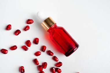 Beyaz arka planda organik nar tohumu özü içeren serum şişesi. Kozmetik doğal serum, cilt bakımı, temel petrol ürünleri. Güzellik ürünleri markası maketi. Düz yatıyordu.