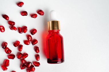Beyaz arka planda organik nar tohumu özü içeren serum şişesi. Kozmetik doğal serum, cilt bakımı, temel petrol ürünleri. Güzellik ürünleri markası maketi. Düz yatıyordu.