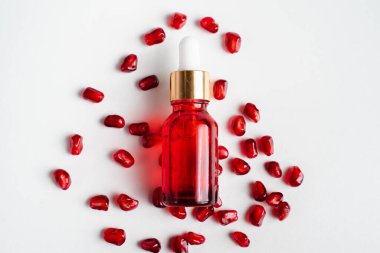 Beyaz arka planda organik nar tohumu özü içeren serum şişesi. Kozmetik doğal serum, cilt bakımı, temel petrol ürünleri. Güzellik ürünleri markası maketi. Düz yatıyordu.