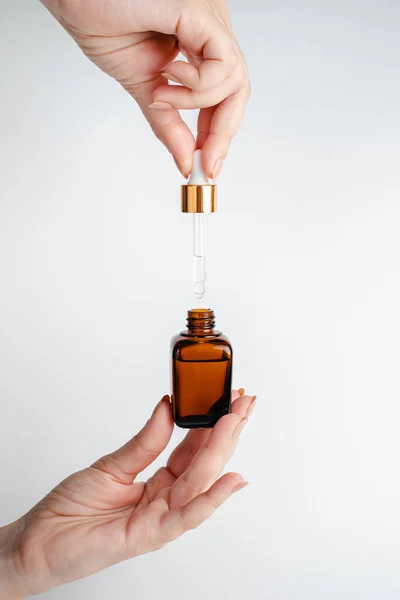 Genç bir kadın elinde yüz serumu tutuyor. Nar özlü yüz sağlığı için esans. Deri gerdirme için antidepresan kozmetik. Kırmızı cam şişeli serum. Organik Vegan Ürünleri. 