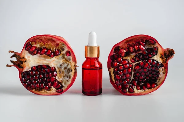 Nar özlü yüz sağlığı için esans. Deri gerdirme için antidepresan kozmetik. Kırmızı cam şişede serum ve nar arkaplanı. Organik Vegan Ürünleri. Metin için yer