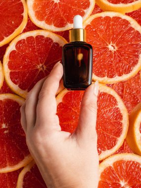 Greyfurt özlü bir şişe. Moda tarzında organik doğal kozmetik ürünü. Deri gerdirme için anti-yaş kozmetikleri. Koyu cam şişede serum. Metin için yer