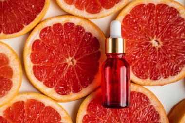 Greyfurt özlü bir şişe. Moda tarzında organik doğal kozmetik ürünü. Deri gerdirme için anti-yaş kozmetikleri. Kırmızı cam şişede serum. Metin için yer