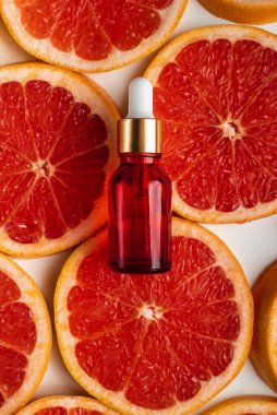 Greyfurt özlü bir şişe. Moda tarzında organik doğal kozmetik ürünü. Deri gerdirme için anti-yaş kozmetikleri. Kırmızı cam şişede serum. Metin için yer