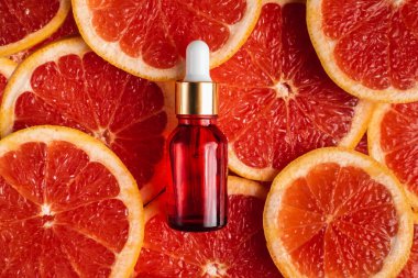 Greyfurt özlü bir şişe. Moda tarzında organik doğal kozmetik ürünü. Deri gerdirme için anti-yaş kozmetikleri. Kırmızı cam şişede serum. Metin için yer