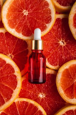 Greyfurt özlü bir şişe. Moda tarzında organik doğal kozmetik ürünü. Deri gerdirme için anti-yaş kozmetikleri. Kırmızı cam şişede serum. Metin için yer