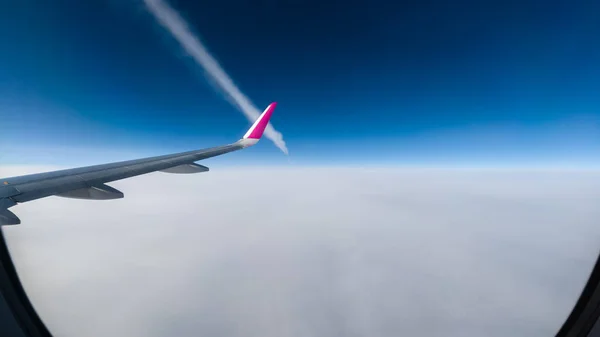 Bulutların üzerindeki bir uçağın ters izi. Pencere deliğinden görüntüle