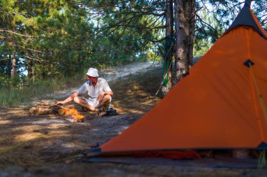 Adam çadırının yakınındaki bir ateşe dallar atıyor.
