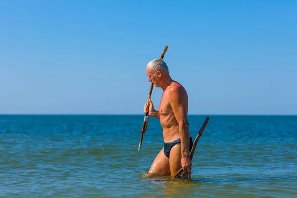 Bıçaktan yapılmış mızraklı ve sopalı bir adam vatozları avlar..